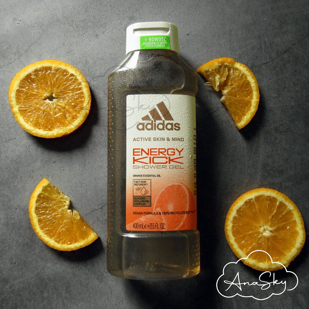 butelka żelu pod prysznic adidas na tle szarym wśród pomarańczy